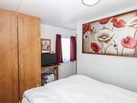 A bedroom with a bed, wardrobe, and television at Whispering Meadows - 104 Hemsby