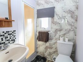 A bathroom with a sink, toilet, and shower at Whispering Meadows - 104 in Hemsby