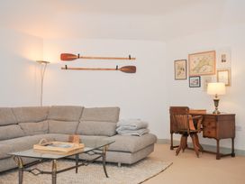 A living room with a sofa, lamp, desk, and pictures at Cribba in Port Isaac