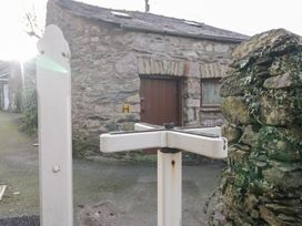 A stone building with a door beside a signpost in Grange-over-Sands