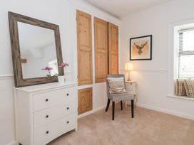 A bedroom featuring a mirror, chest of drawers, chair, and framed artwork at No.2 The Flags, Grange-over-Sands