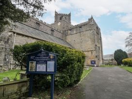 An exterior view of a church with a signboard and pathway at No.2 The Flags in Cartmel