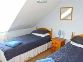 A bedroom with two single beds and a nightstand at Morlais in Rhosneigr