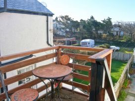 A balcony with a table and chairs overlooking a garden at Morlais in Rhosneigr