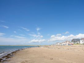 A beach with a view of houses beside the ocean at Morlais in Rhosneigr