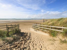 A beach entrance with sand and grass leading to the water at Morlais in Rhosneigr