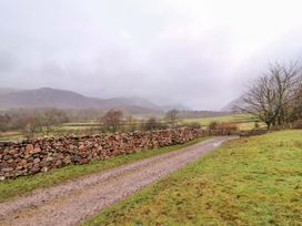 A dirt road beside a stone wall with mountains in the background at Easthwaite Cottage in Holmrook near Easthwaite Farm