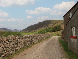 A view of a dirt road alongside a stone wall with mountains in the background at Easthwaite Cottage Nether Wasdale near Wastwater