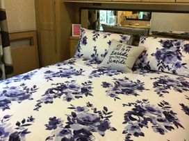 A bedroom with a bed and floral bedspread at Plot 293 Caravan