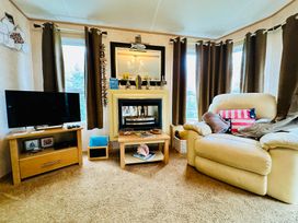 A living room with a sofa and television at Plot 293 Caravan Weybourne near Sheringham