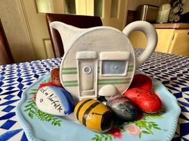 A teapot shaped like a caravan with decorative stones on a plate at Plot 293 Caravan Weybourne near Sheringham