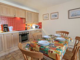 A kitchen with cabinets, countertop, appliances, and dining table at 3 The Salcombe, Salcombe