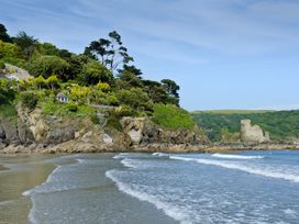 A beach with waves and cliffs featuring trees and structures at 3 The Salcombe, Salcombe