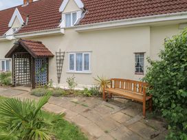 A garden with a wooden bench and lattice structure at Driftway Stables Retreat in Diss