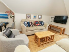 A living room with a sofa, coffee table, television and wall art at Flat 7 Weymouth