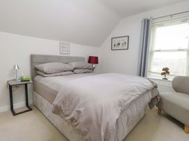 A bedroom featuring a bed, bedside table, lamp, and window at Flat 7 in Weymouth