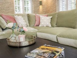 A living room with a sofa and flowers on a table at Low House Cottage Ayside near Newby Bridge