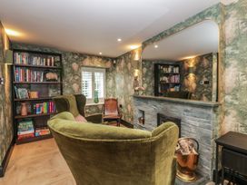 A snug with a bookshelf and fireplace at Low House Cottage Ayside near Newby Bridge