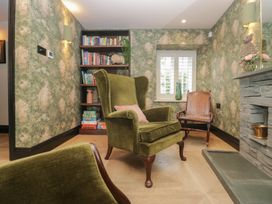 A snug with a wingback chair and bookshelves at Low House Cottage Ayside near Newby Bridge