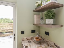 A kitchen corner with a shelf and cookies under a glass dome at Low House Cottage Ayside near Newby Bridge
