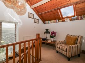 A snug with an armchair and books on a shelf at The Wren's Nest in Ross-on-Wye
