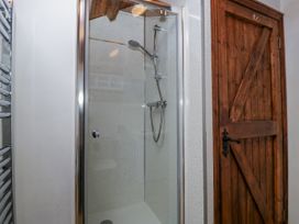 A shower with glass enclosure and wooden door at The Wren's Nest in Ross-on-Wye