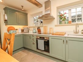 A kitchen with cabinets, oven, and sink at Bridge House Cottage in Burn Bridge near Harrogate
