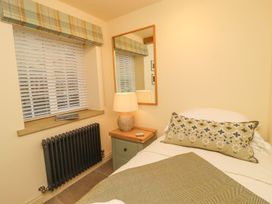 A bedroom with a bed and lamp at Bridge House Cottage in Burn Bridge near Harrogate