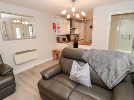 A living room with a sofa and kitchen area at Primrose Cottage in Chathill