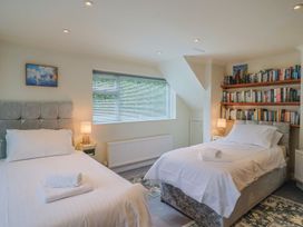 A bedroom with two beds and a bookshelf at Hawksdown in Lyme Regis
