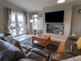 A living room with a sofa and coffee table at Holly Lodge in Lloc near Caerwys