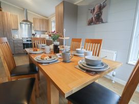 A dining room with a wooden table set for a meal at Holly Lodge in Lloc near Caerwys