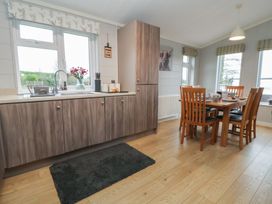A kitchen with sink and dining area at Holly Lodge in Lloc near Caerwys