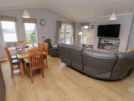 A living room with a dining table and sofa at Holly Lodge in Lloc near Caerwys