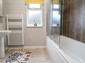 A bathroom with a bathtub, sink, and towel rail at Holly Lodge in Lloc near Caerwys