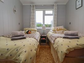 A bedroom with twin beds and a bedside table at Holly Lodge Lloc near Caerwys