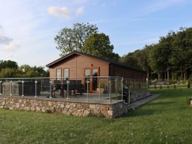 A cabin with a deck and hot tub at Holly Lodge near Lloc in Caerwys