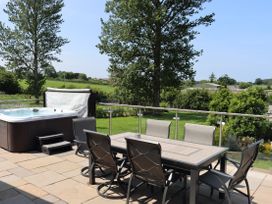 An outdoor area with a hot tub and dining table at Holly Lodge in Lloc near Caerwys