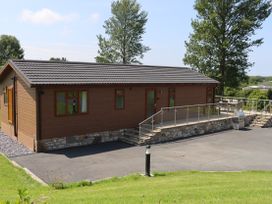 An outdoor area with a wooden lodge and patio at Holly Lodge in Lloc near Caerwys
