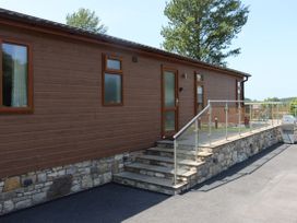 An outdoor view of a wooden lodge with steps and railing at Holly Lodge Lloc near Caerwys