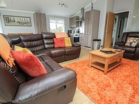 A living room with a sofa and coffee table at Pine Lodge in Lloc near Caerwys