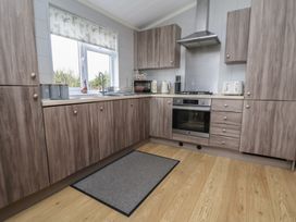 A kitchen with wooden units and stainless steel appliances at Pine Lodge in Lloc near Caerwys
