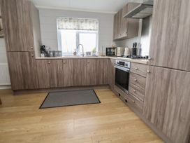 A kitchen with a sink, microwave, and oven at Pine Lodge in Lloc near Caerwys