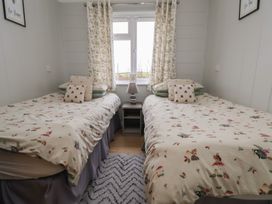 A bedroom with two beds and a lamp at Pine Lodge in Lloc near Caerwys