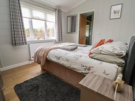 A bedroom with a bed and curtains at Pine Lodge in Lloc near Caerwys