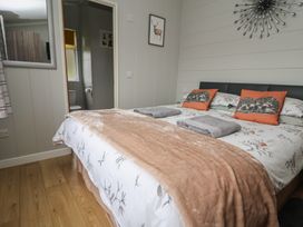 A bedroom with a bed and en-suite bathroom at Pine Lodge in Lloc near Caerwys