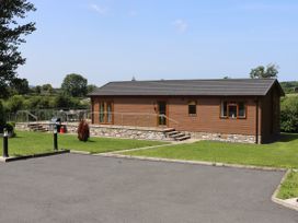 A house with a deck and grass area at Pine Lodge in Lloc near Caerwys