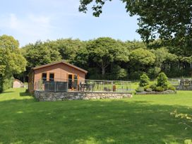 A lodge with deck and table in a garden at Pine Lodge in Lloc near Caerwys