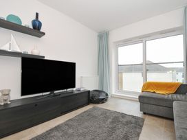 A living room with a television, shelf, and sofa at Sea Snug in Newquay