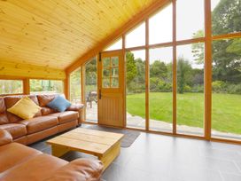 A conservatory with a sofa and wooden table at The Cider Barn at Home Farm Down Thomas near Wembury